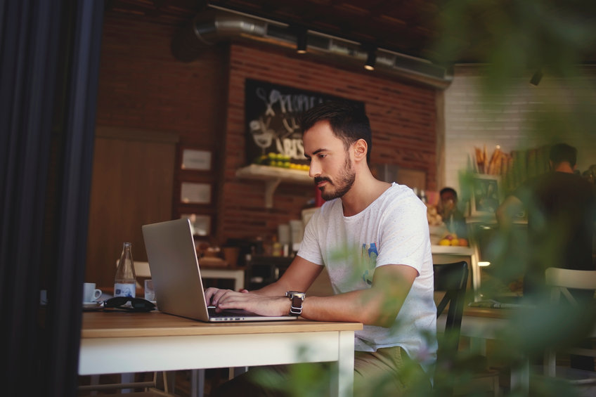 Young man sitting in a cafe drinking a coffee and reading about Bitcoin being boring - why it is, and why it isn't.