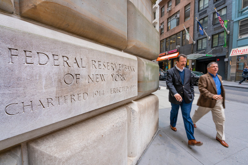 Man walking past the Federal Reserve Bank of New York. It is responsible for implementing monetary policy in the United States.