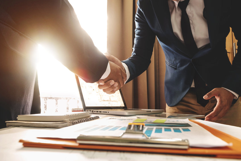 Two confident business man shaking hands during a meeting in the office, success, dealing, greeting and partner in sun light