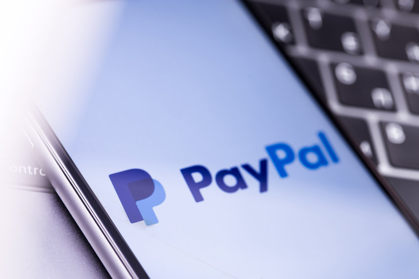 PayPal company logo on a smart phone with a white screen and a keyboard in the background.