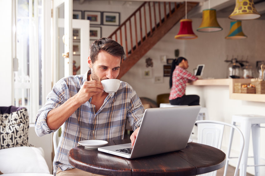 Young man using laptop in a cafe