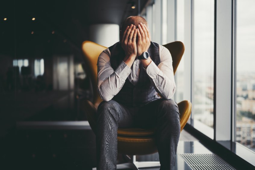 Crypto trader sitting in a yellow chair with his head in his hands because exchanges are insolvent