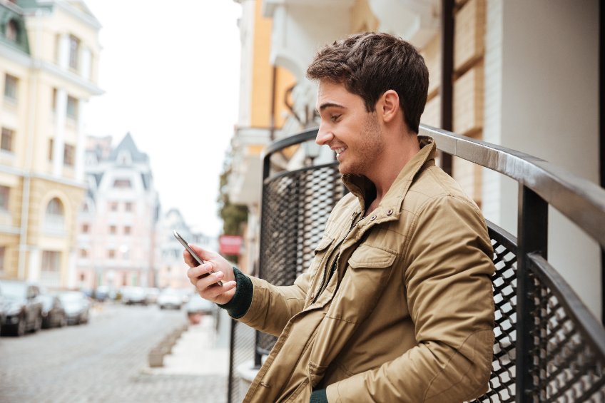 Young man in the street reading about Bitcoin's price activity on his phone.