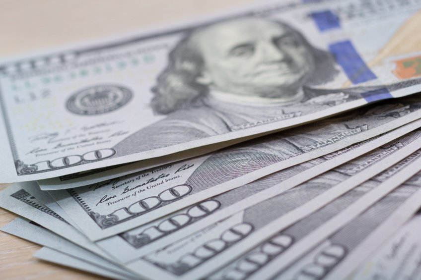 $100 USD notes lying on a wooden table representing Celsius paying off its loan from Aave.