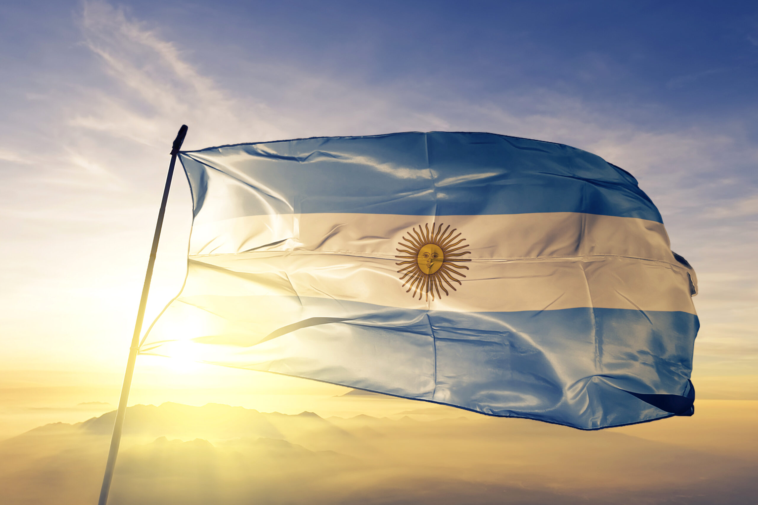 Flag of Argentina flying high in the wind with the Sun in the background.