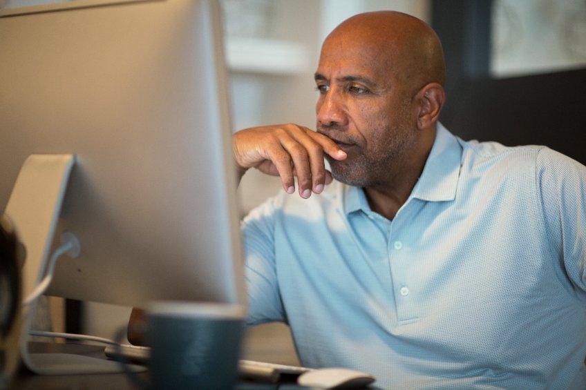 Image of a man looking at a monitor in a pensive mood.