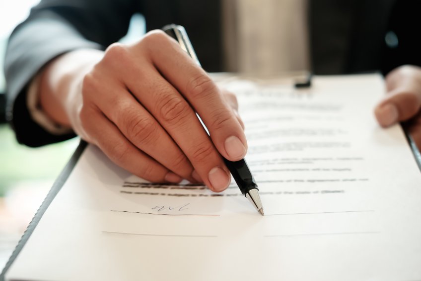 Image of a man holding a pen over a legal contract.