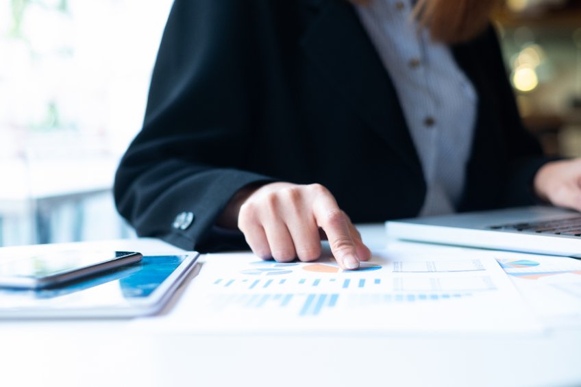 Image of a man putting his hand on a stack of papers and charts.