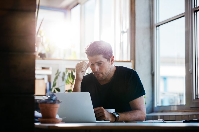 A worried investor looks at his laptop indicating a major loss from an investment.