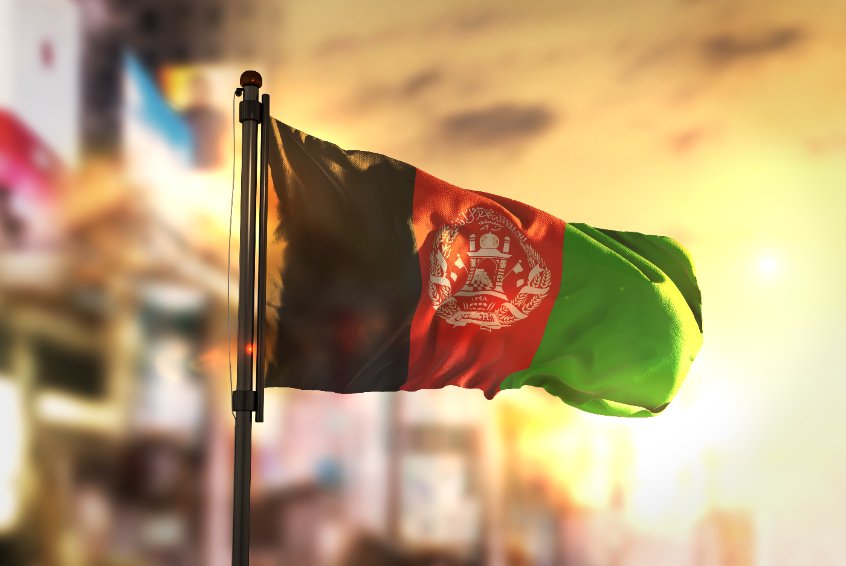Afghanistan flag against city blurred background at sunrise backlight
