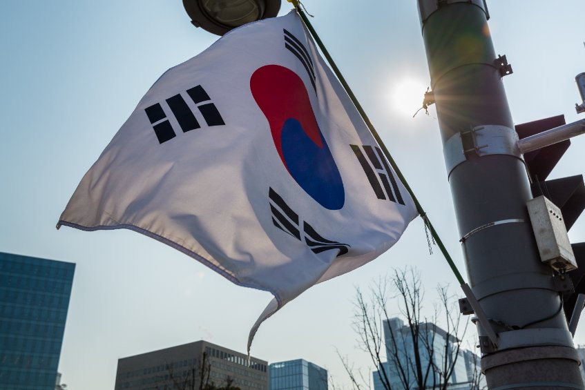 Korean national flag hanging at the post against the sun with background of skylines in seoul