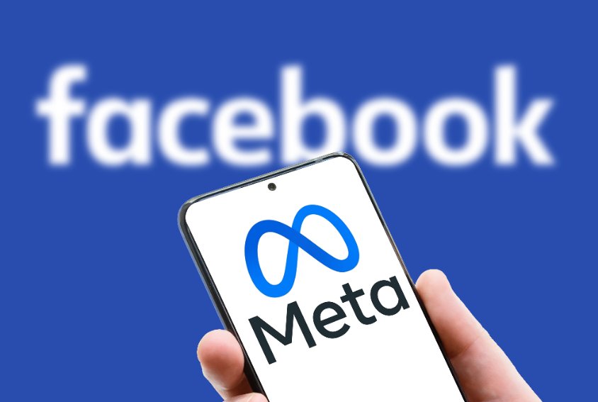 meta logo on screen of mobile phone on facebook word background