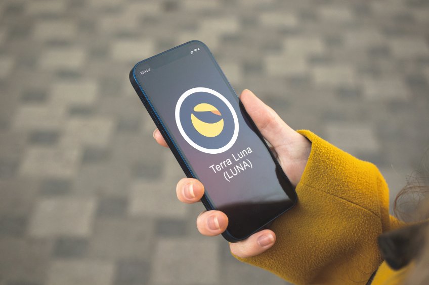 Terra luna cryptocurrency symbol, logo. business and financial concept. hand with smartphone, screen with crypto icon closeup