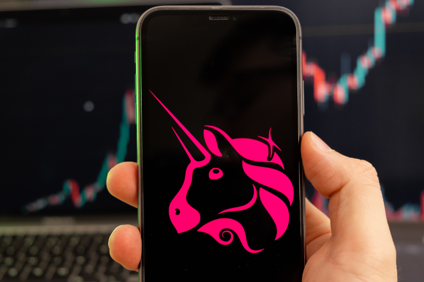 Uniswap uni cryptocurrency logo on the screen of a smartphone in mans hand