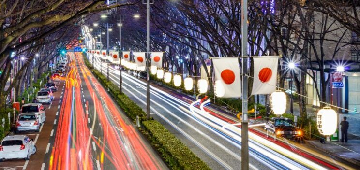 Harajuku tokyo japan traffic flows below japanese flags at night.