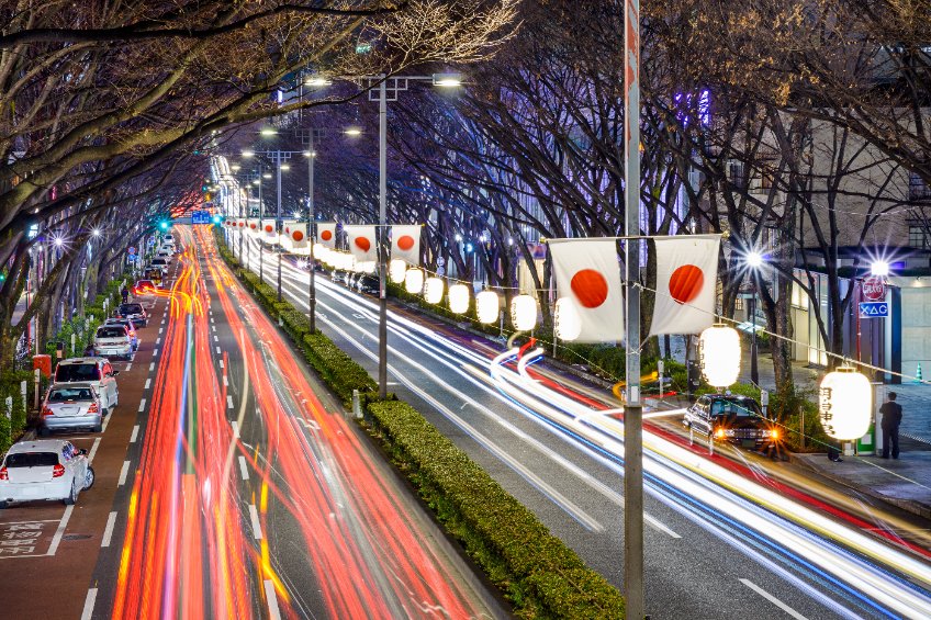 Harajuku tokyo japan traffic flows below japanese flags at night.