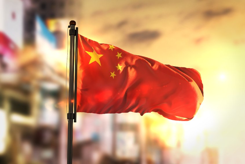 China flag against city blurred background at sunrise backlight
