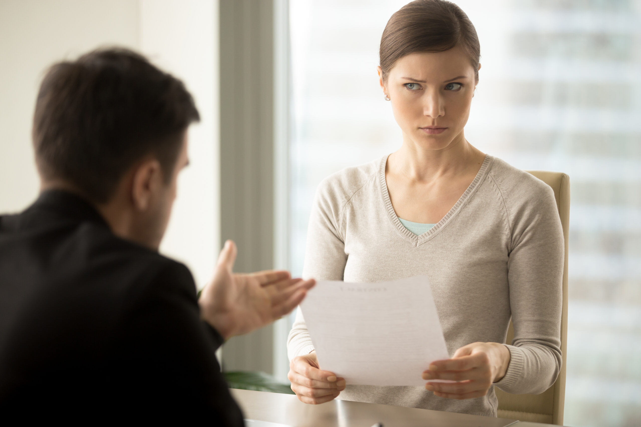 A businesswoman looking at a report with a dissatisfied look on her face indicating that the news are either bad, unexpected, or both.