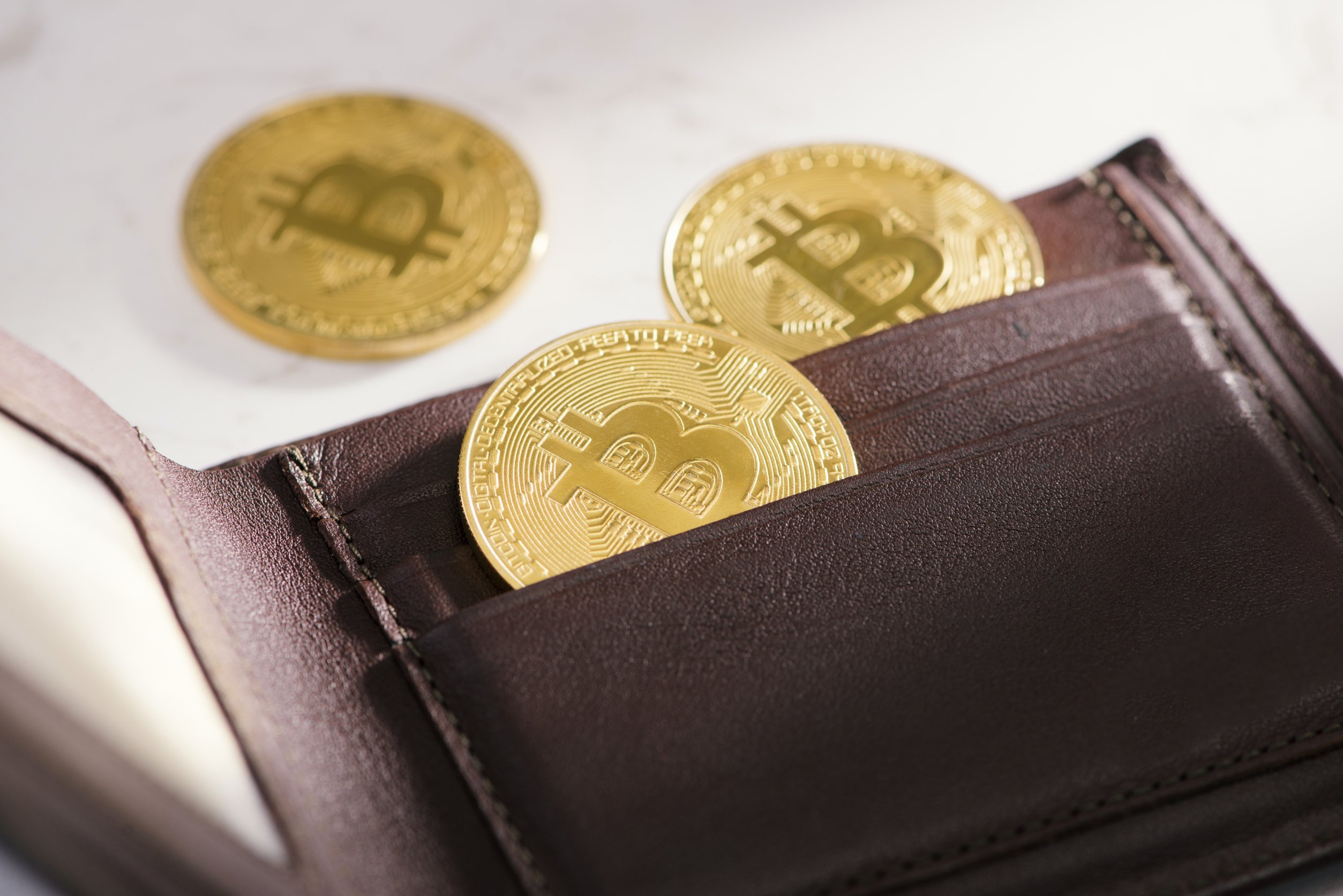 BTC coins falling out of a leather wallet.