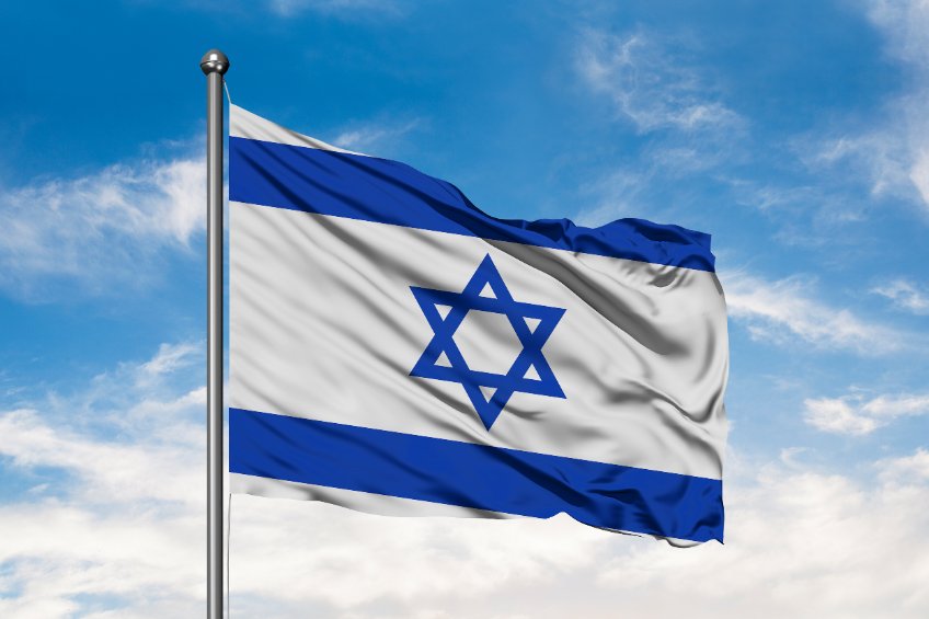 Flag of Israel waving in the wind against white cloudy blue sky. Israeli flag.