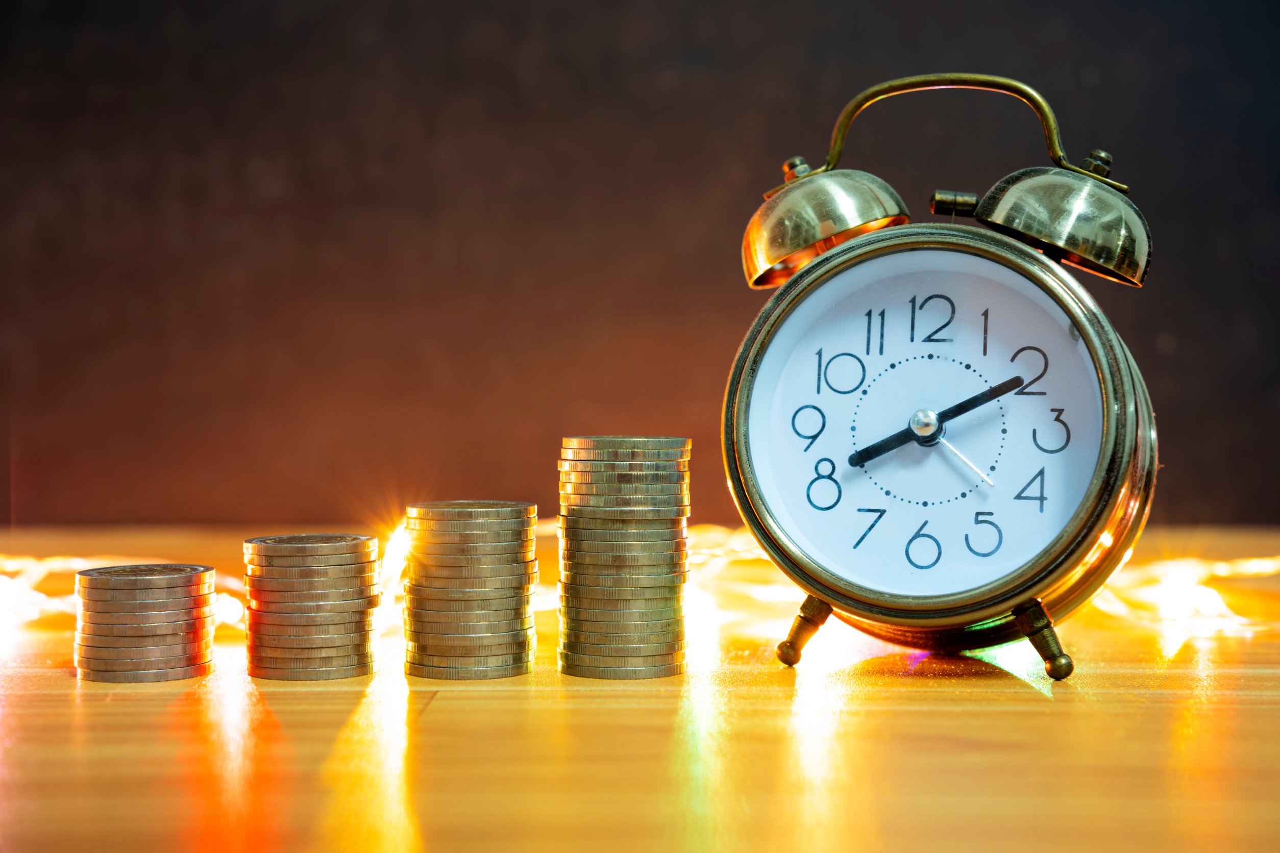 Several stacks of coins next to an old alarm clock demonstrating that the exploit uses the old ETH Alarm Clock contract.