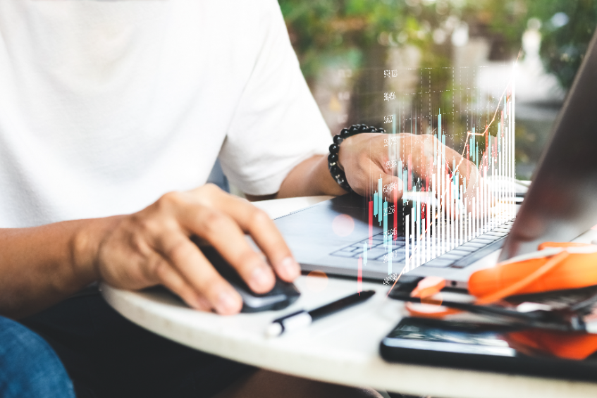 Casual young adult researching the trading volume of various cryptocurrencies on a laptop.