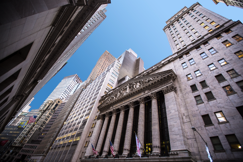 Wall Street with sky-rise buildings and a blue sky in the background.