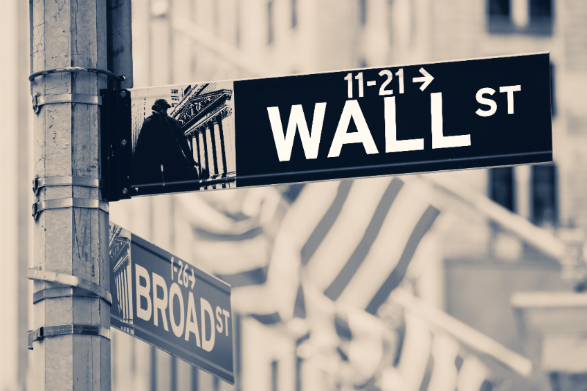 Vintage looking Wall street sign in New York City with out of focus buildings and american flags on the background