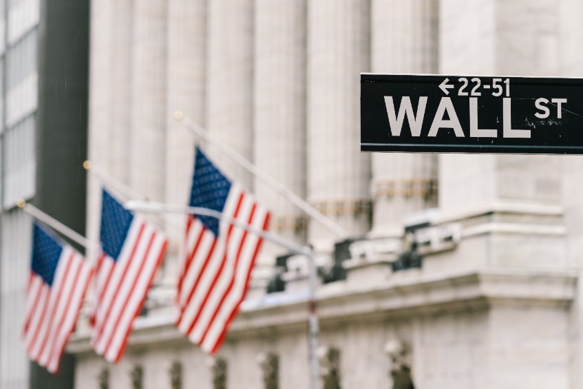 Wall Street sign post with American national flags in background