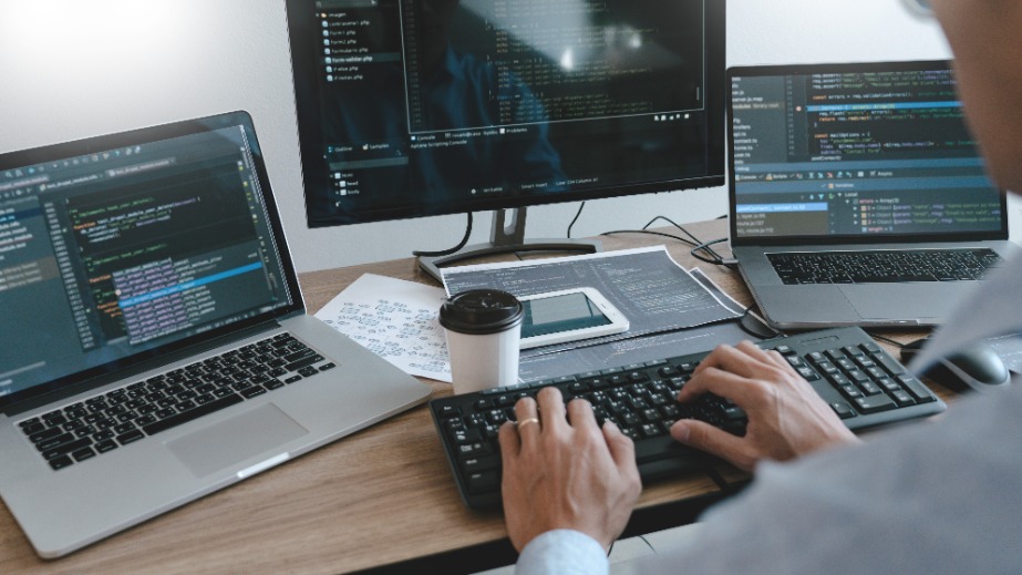 Programmer working On Computer In IT Office Typing Data Coding in software and checking code on computer screen