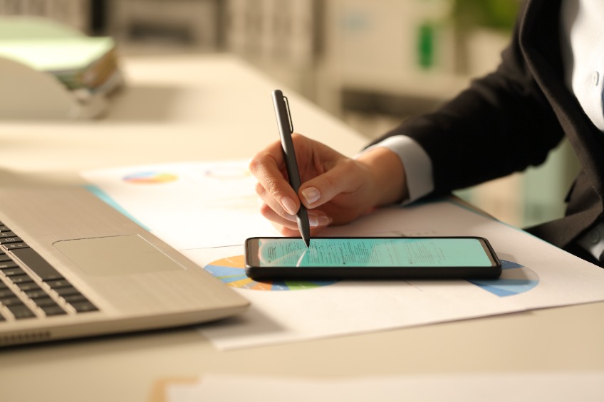 hands filling out form with stylus on smart phone at night in the office