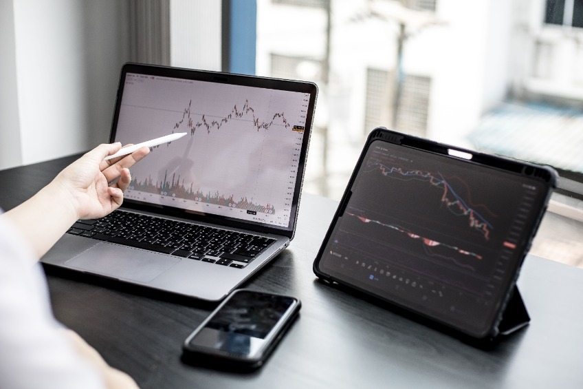 A stock investor holding a pen pointing to a laptop screen