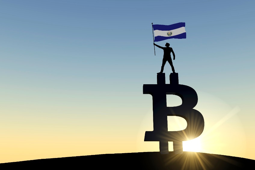 Person waving an el salvador flag standing on top of a bitcoin cryptocurrency