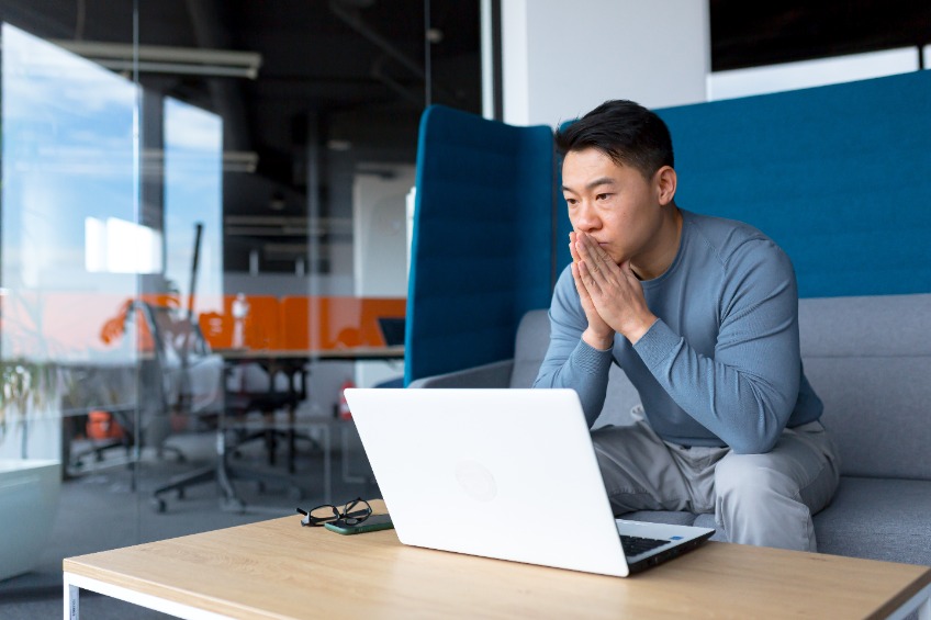 Pensive businessman in modern office working on laptop