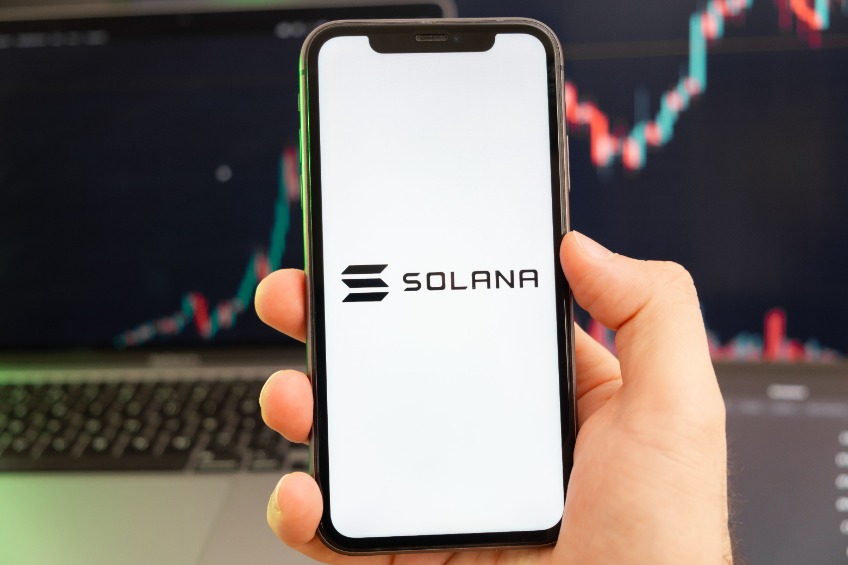 Solana SOL cryptocurrency logo on the screen of a smartphone in mans hand with a growing trend