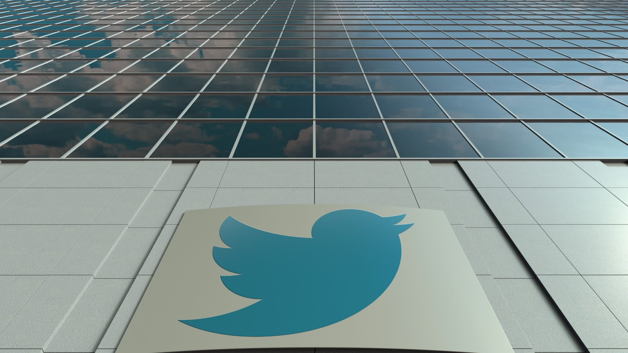 Twitter logo on the side of a glass building.