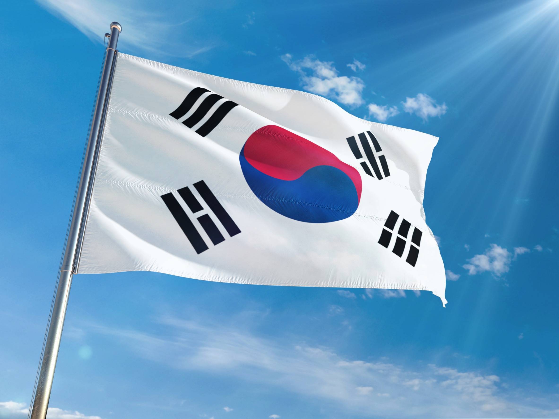 South Korean flag flying freely in the wind against a clear blue sky.