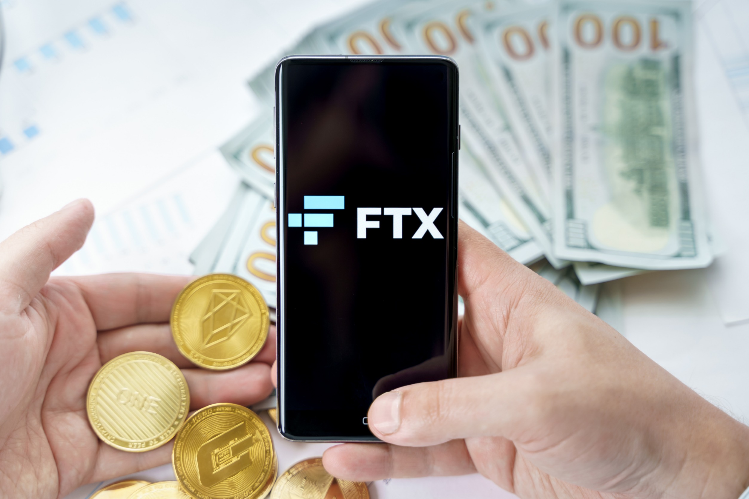 FTX logo on a phone screen surrounded by money