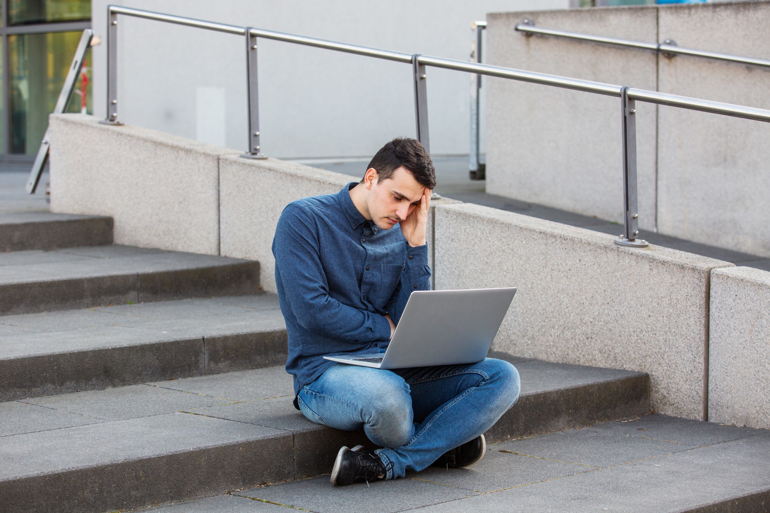Stressed student preparing for an exam in campus area sitting on university stairs.