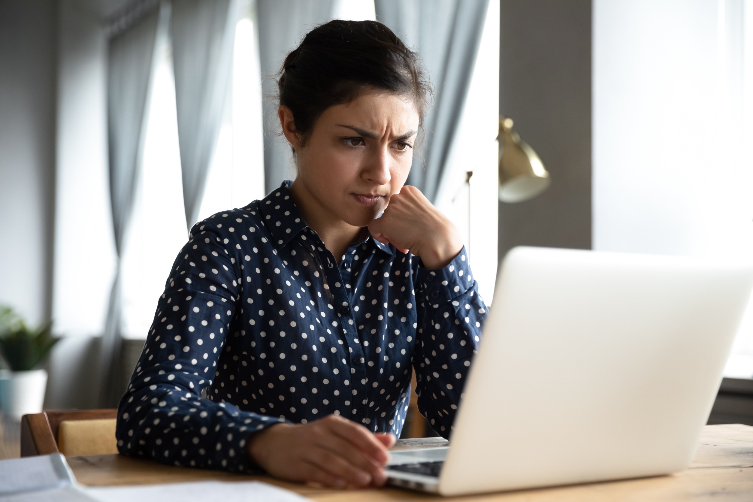 Concerned puzzled young indian woman student professional use look at laptop at home office