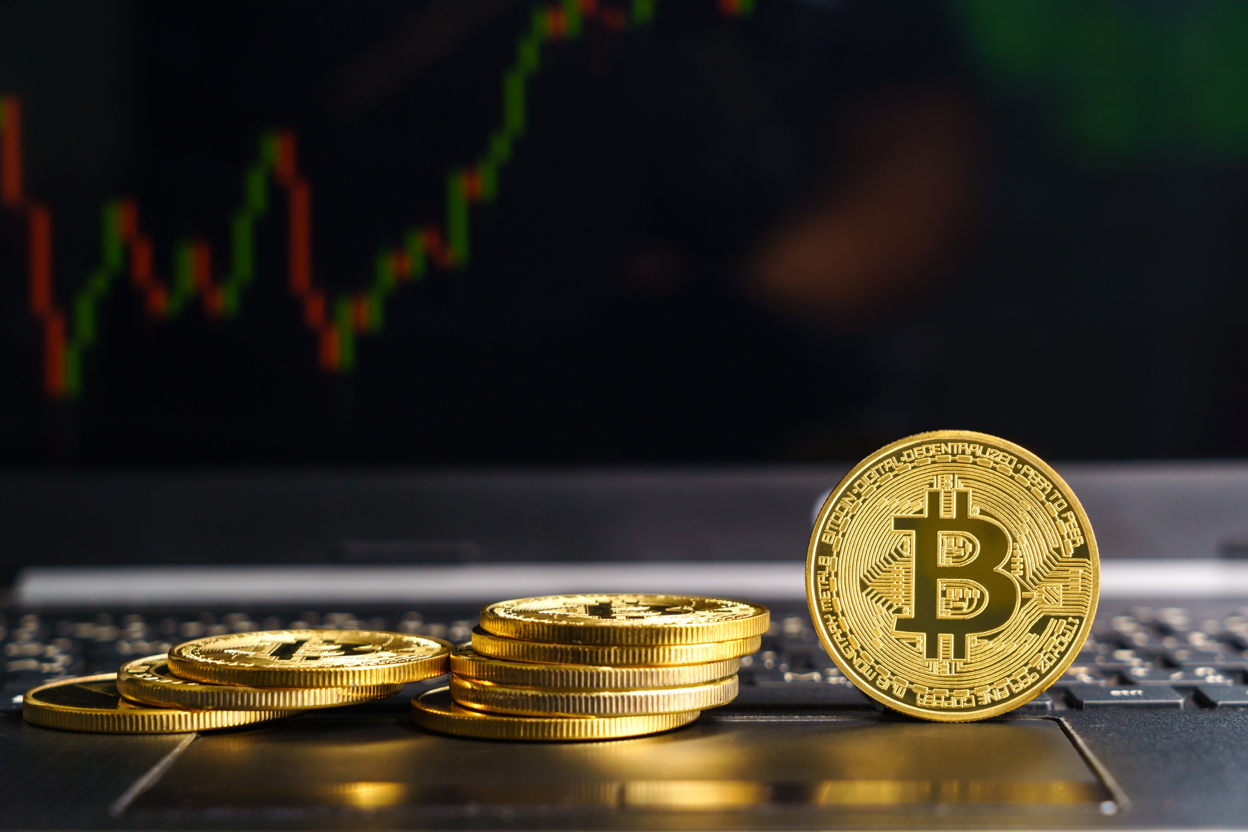 Phisical representation of a BTC on a keyboard in front of a price chart.