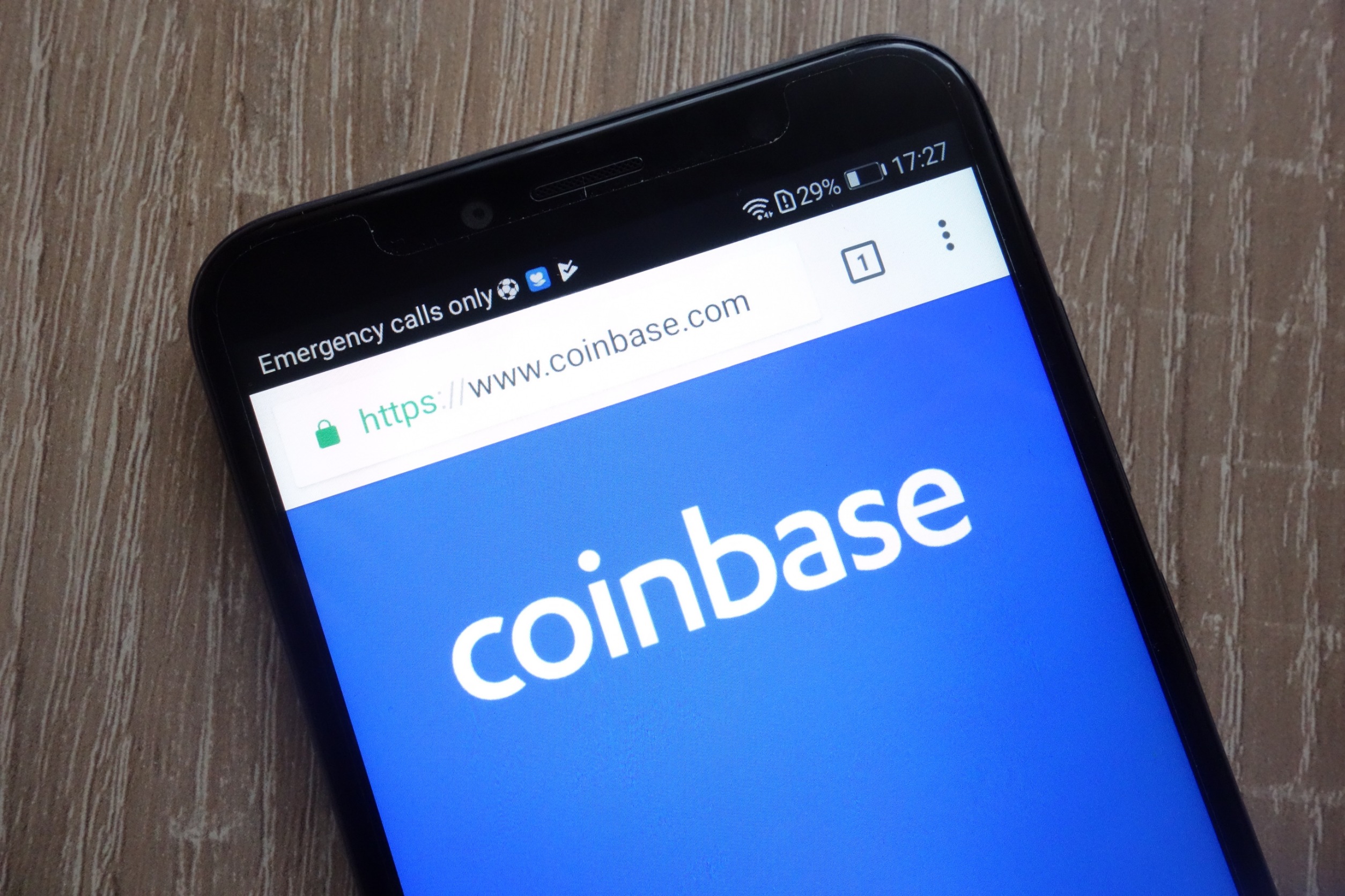 "Coinbase" on the screen of a phone on a desk.