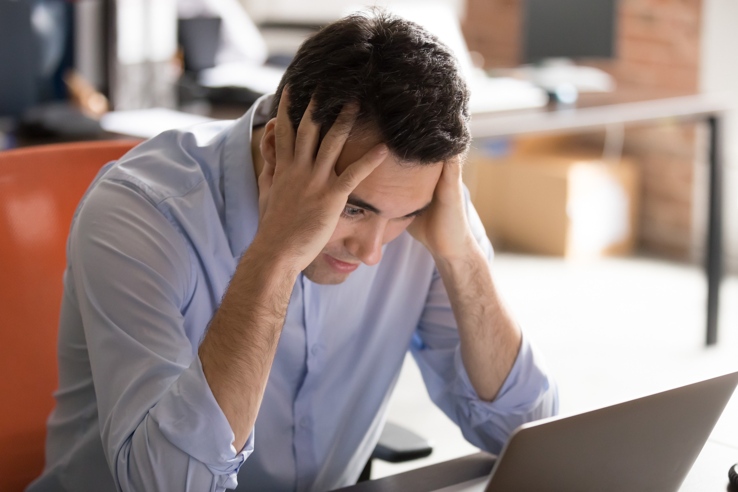 Businessman sitting at desk make big eyes hold head with hands look at pc screen feels stressed having problems