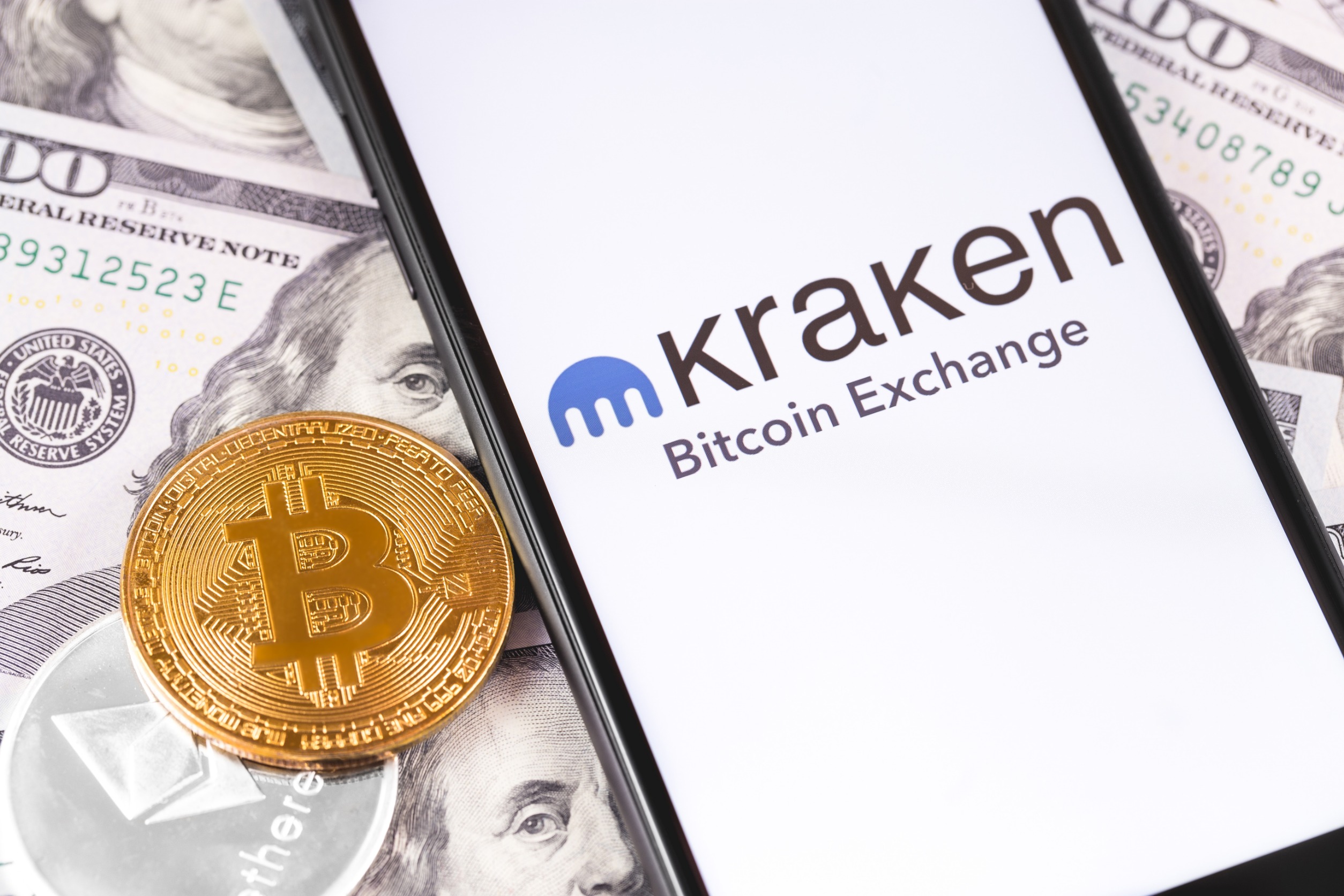 "KRAKEN" on a phone screen on a pile of cash