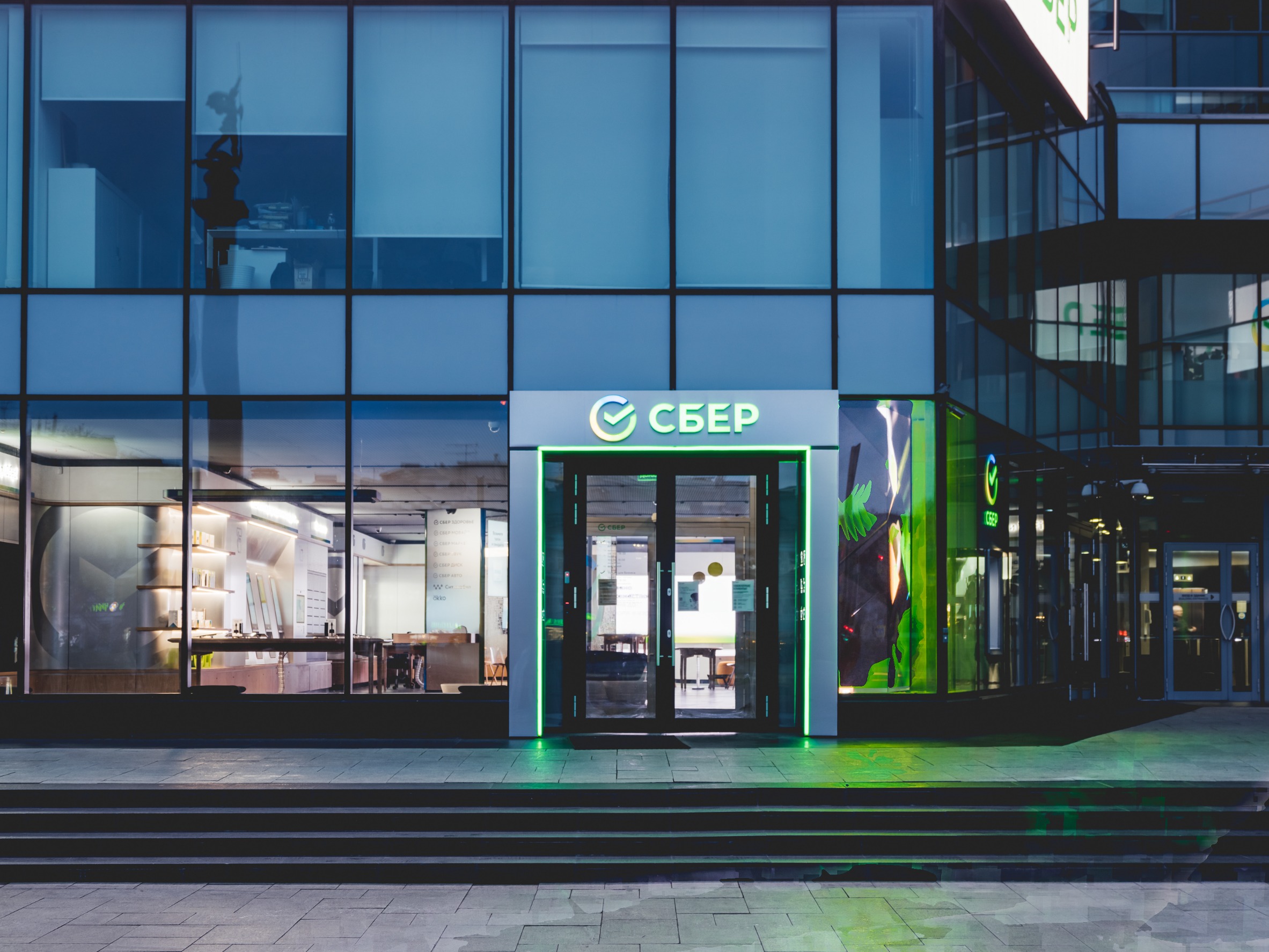 Facade of modern building. Entrance of Sberbank office with new glowing logo.