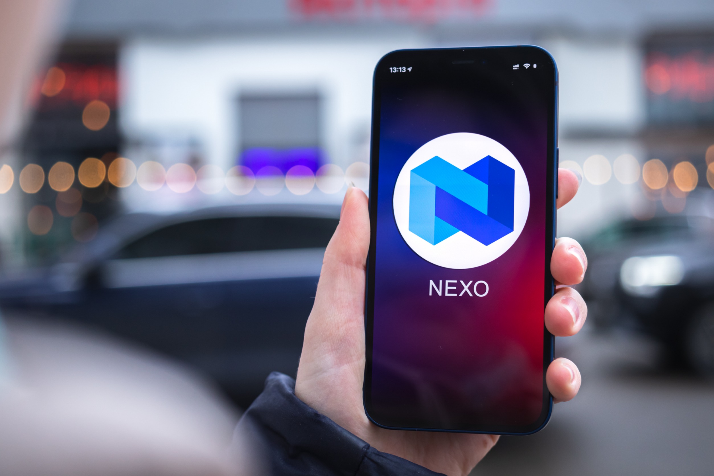 "Nexo" on the screen of a phone held in a hand.