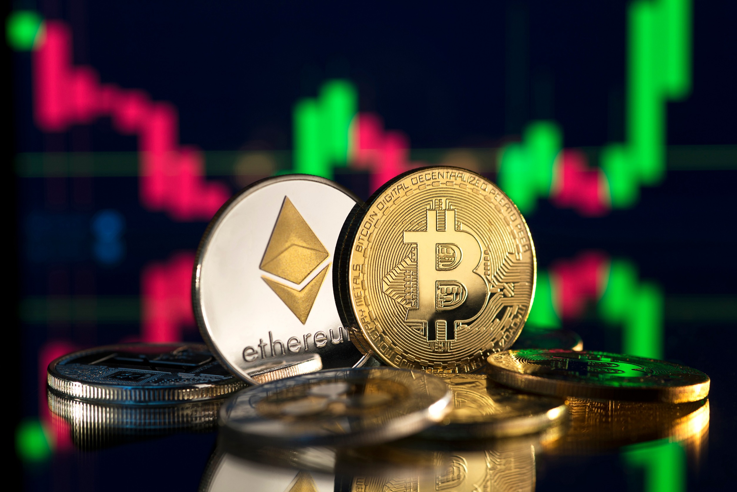 Physical representation of BTC and ETH in front of a screen showing a price chart that surges upward after a time in the red.