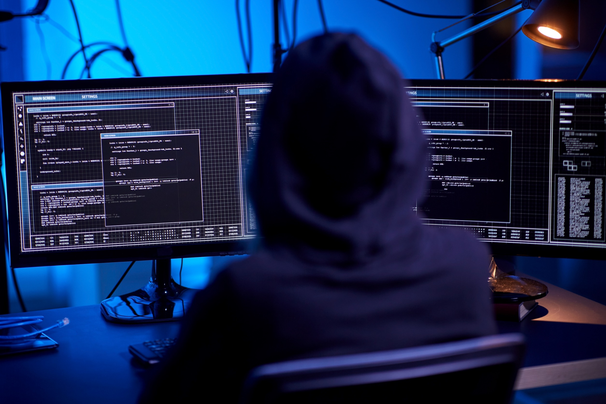 Hacker in a hoodie sitting at his computer.