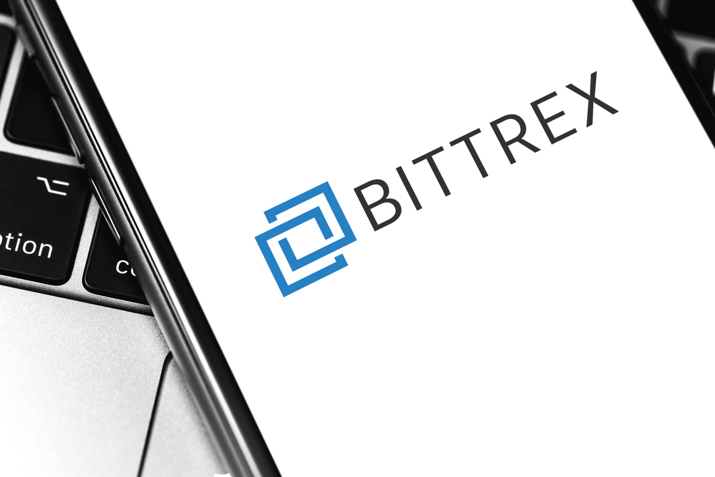 Smartphone resting on a laptop keyboard and displaying "BITTREX"