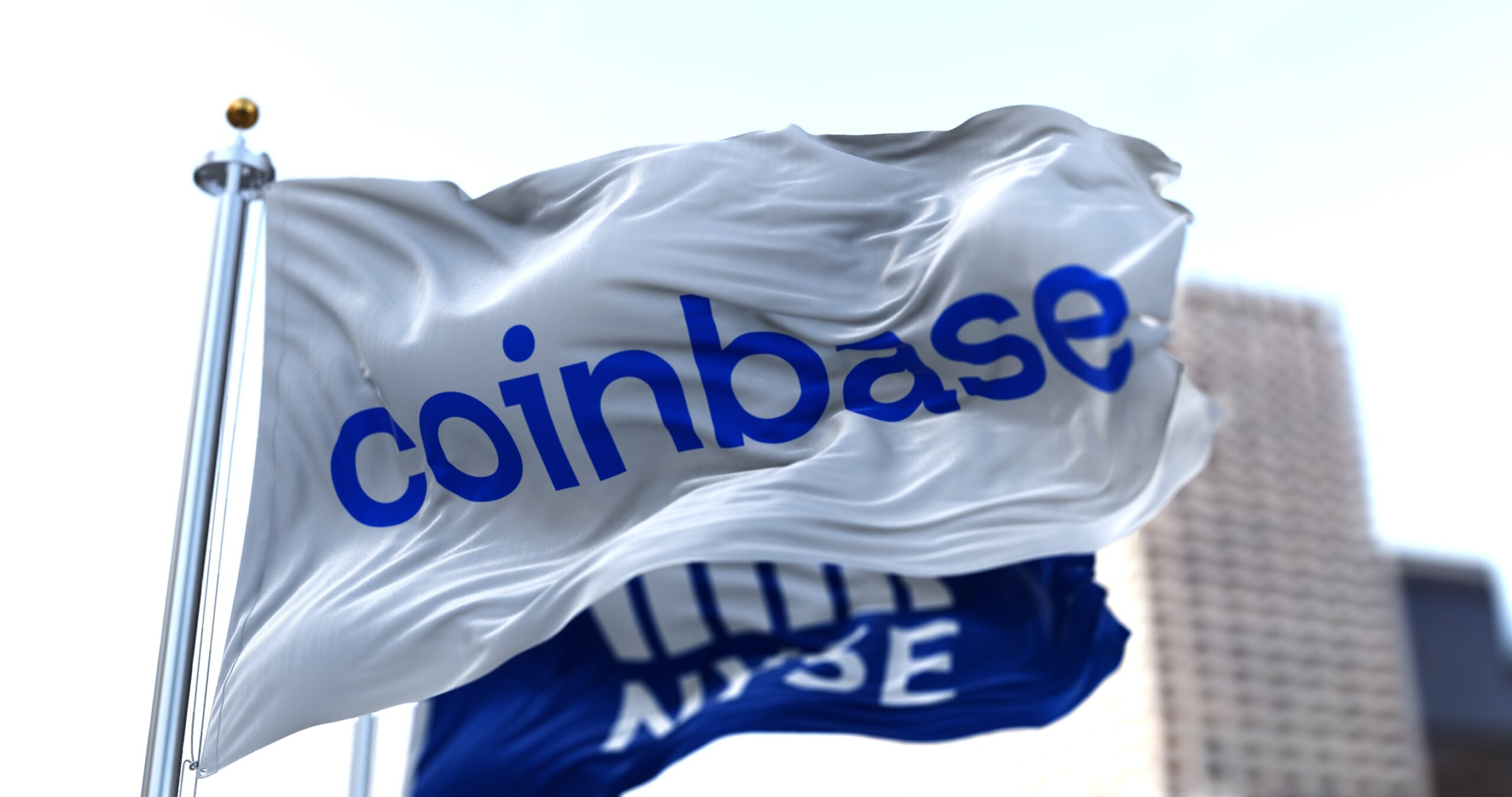 Flags of Coinbase and NYSE flying in the wind. On April 14, 2021, Coinbase went public on the Nasdaq exchange via a direct stock listing